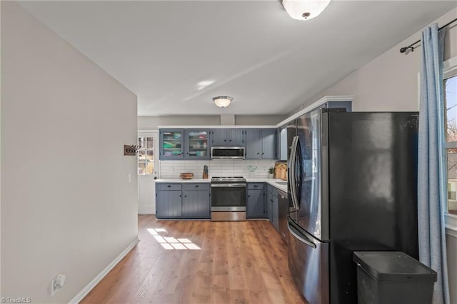 kitchen with decorative backsplash, light wood-type flooring, a wealth of natural light, and appliances with stainless steel finishes