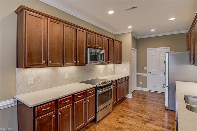 241 Collingswood Dr, Winston-Salem, NC 27127 - kitchen with stainless steel appliances, crown molding, recessed lighting, wood finished floors, and tasteful backsplash