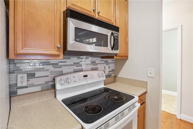 kitchen with white range with electric stovetop, tasteful backsplash, and light hardwood / wood-style flooring