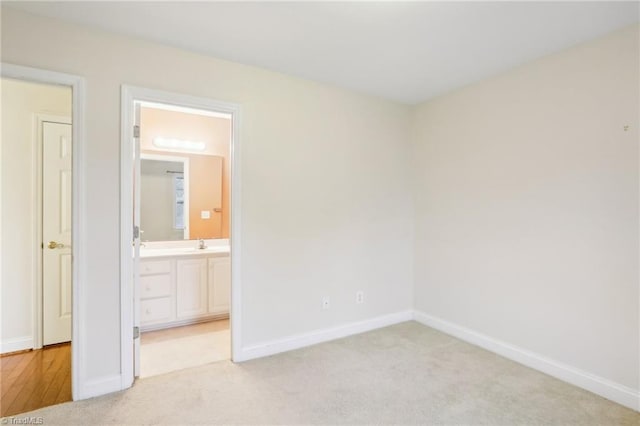 unfurnished bedroom with ensuite bath and light colored carpet