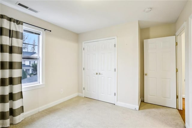 unfurnished bedroom with a closet and light colored carpet