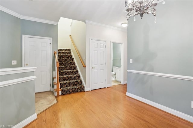 stairs with hardwood / wood-style floors, a notable chandelier, and ornamental molding