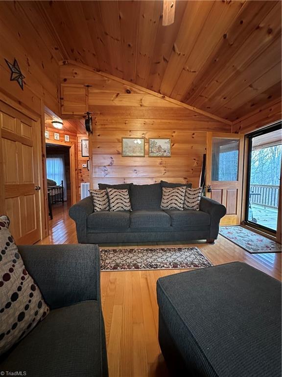 living room with ceiling fan, wood ceiling, vaulted ceiling, and hardwood / wood-style flooring