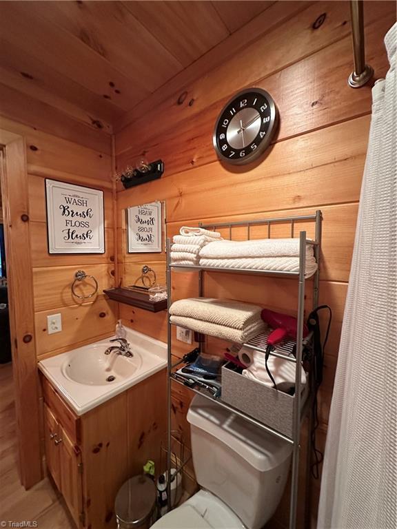 bathroom with vanity, wooden ceiling, and wooden walls