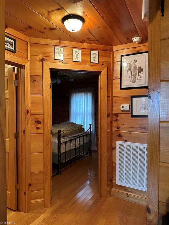 hall with hardwood / wood-style floors, wood walls, and wooden ceiling