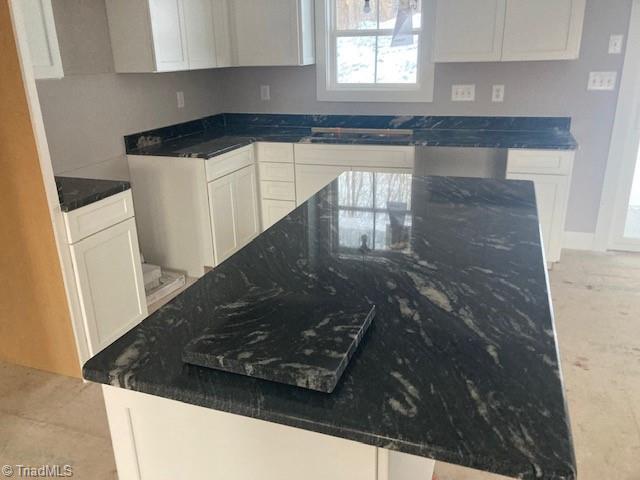 kitchen with dark stone countertops and white cabinetry