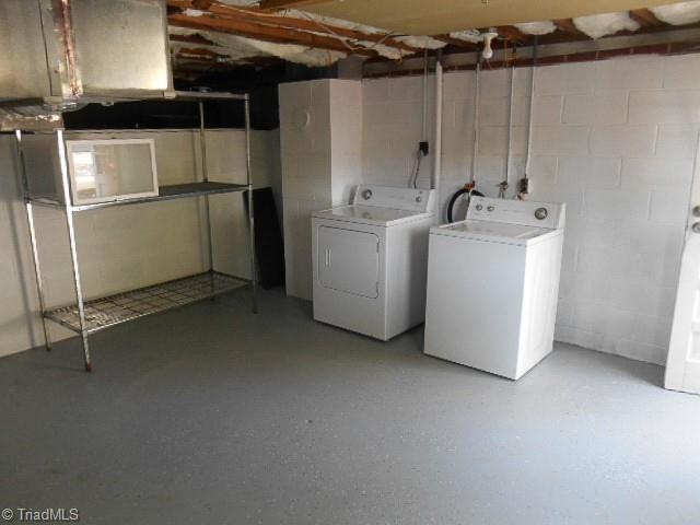 unfinished basement with independent washer and dryer and concrete block wall