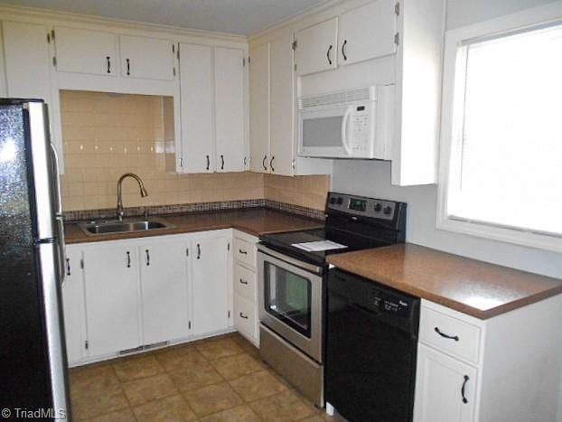 kitchen featuring tasteful backsplash, dark countertops, appliances with stainless steel finishes, white cabinetry, and a sink