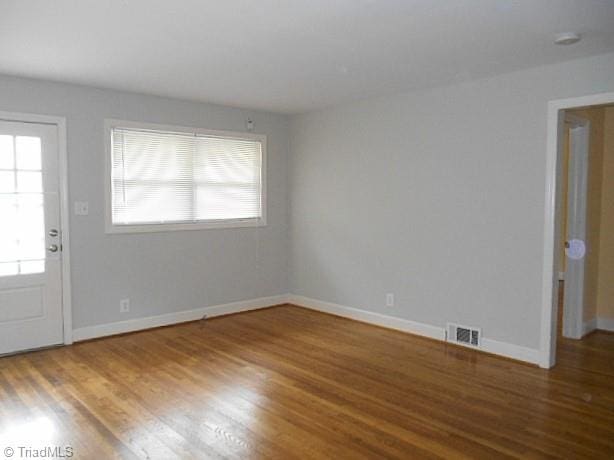 unfurnished room featuring visible vents, baseboards, and wood finished floors