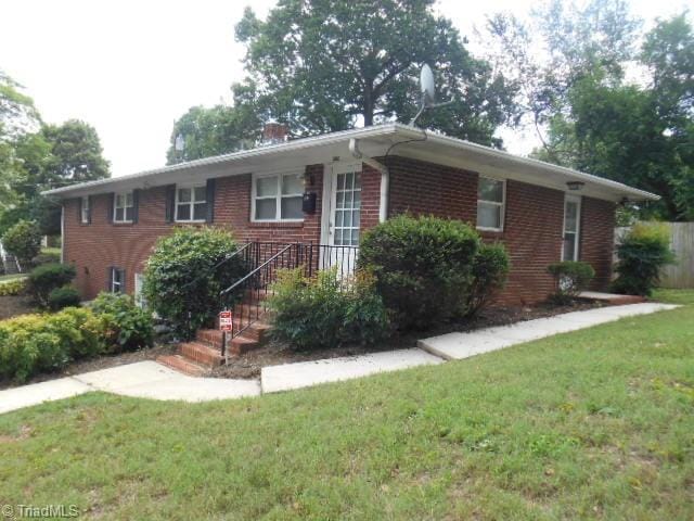 ranch-style house with brick siding, a chimney, and a front yard