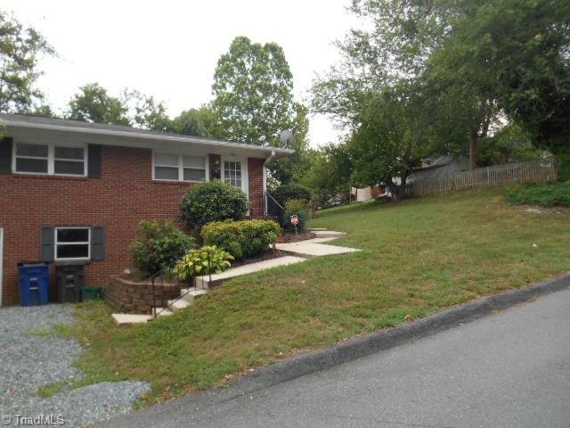 view of front facade featuring brick siding, a front yard, and fence