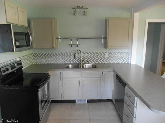 kitchen with decorative backsplash, a peninsula, stainless steel appliances, and a sink