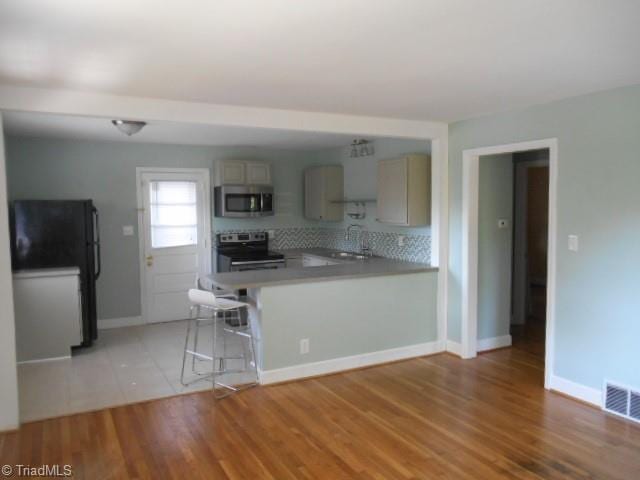 kitchen with visible vents, decorative backsplash, light countertops, light wood-style floors, and appliances with stainless steel finishes