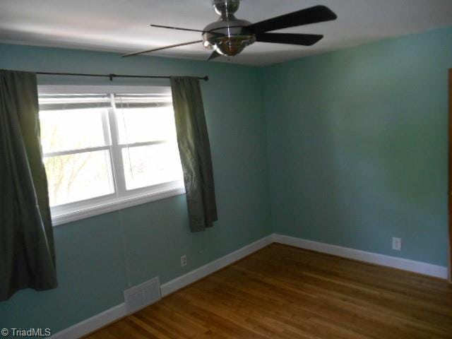 spare room with visible vents, baseboards, wood finished floors, and a ceiling fan