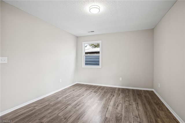 spare room featuring a textured ceiling and dark wood-type flooring