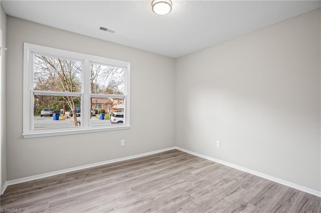 empty room with a textured ceiling and light hardwood / wood-style floors