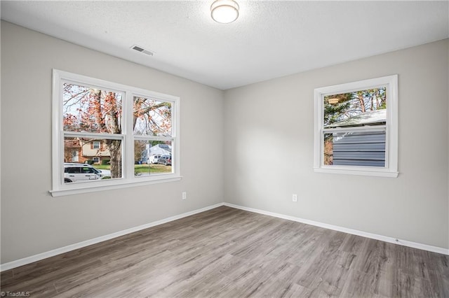 spare room with hardwood / wood-style flooring, a healthy amount of sunlight, and a textured ceiling