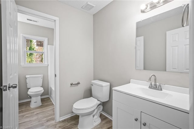 bathroom with hardwood / wood-style floors, vanity, a textured ceiling, and toilet