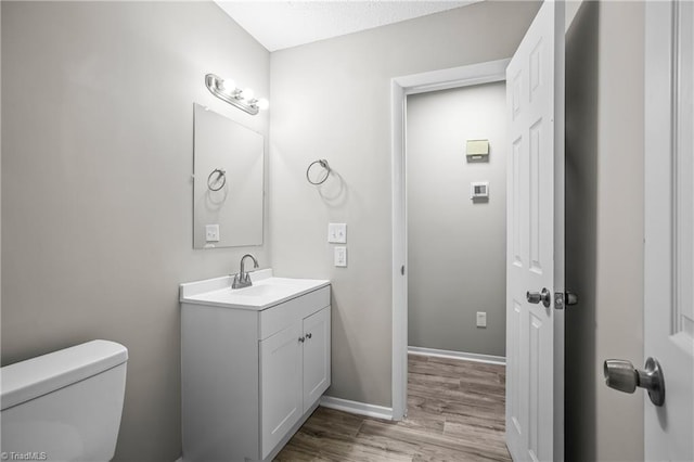 bathroom featuring wood-type flooring, vanity, and toilet