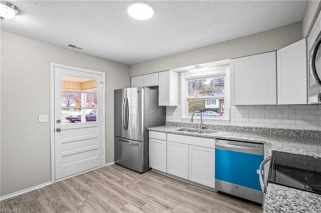 kitchen featuring appliances with stainless steel finishes, white cabinetry, plenty of natural light, and sink