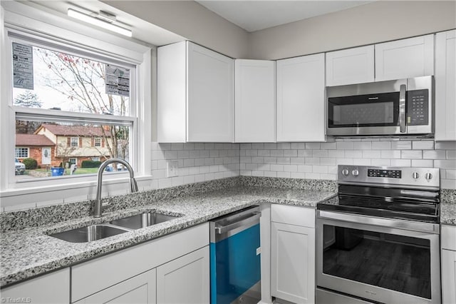 kitchen featuring light stone countertops, sink, white cabinets, and stainless steel appliances