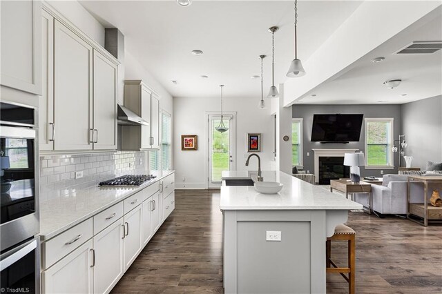 kitchen featuring stainless steel gas stovetop, open floor plan, decorative backsplash, dark wood-style flooring, and recessed lighting
