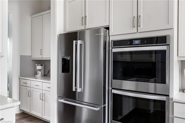 kitchen with appliances with stainless steel finishes, tasteful backsplash, white cabinets, and light stone countertops