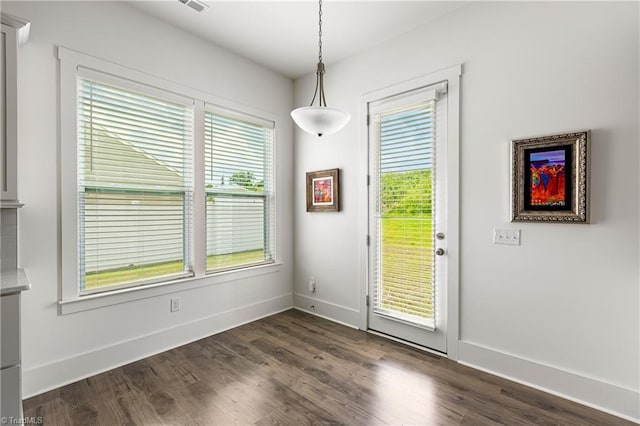 unfurnished dining area with baseboards and dark wood-style floors