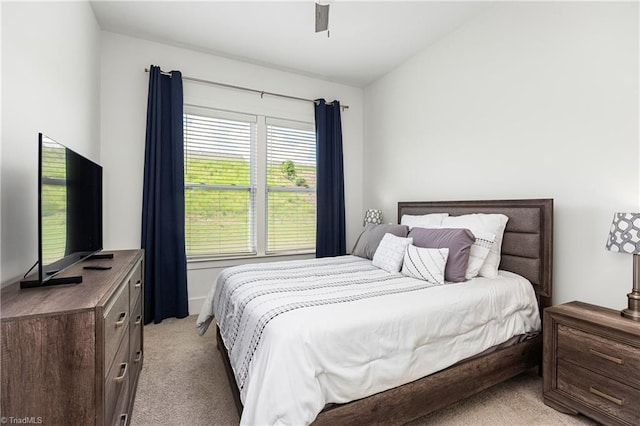 bedroom featuring light colored carpet, vaulted ceiling, and a ceiling fan