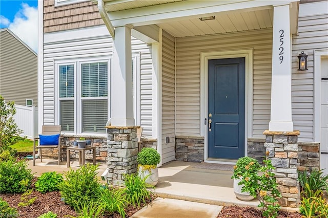 doorway to property with covered porch and stone siding