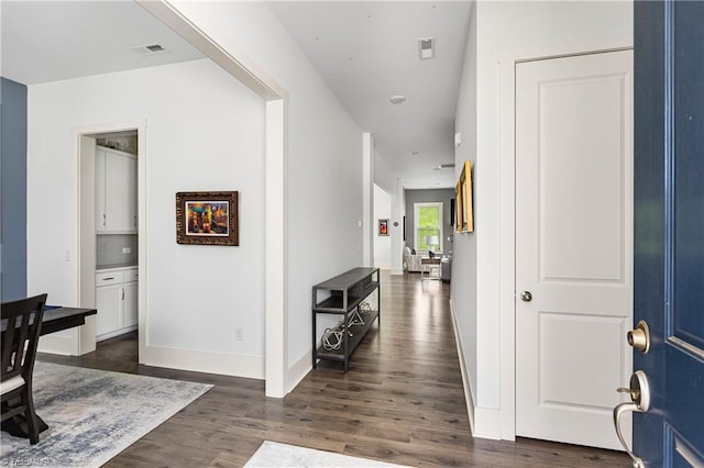 corridor with dark wood finished floors and baseboards