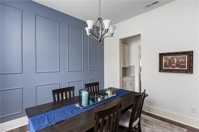 dining area with a chandelier, wood finished floors, and baseboards