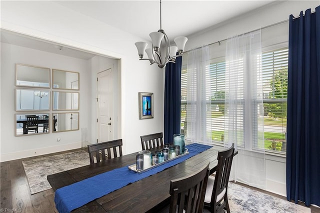 dining room featuring a chandelier, healthy amount of natural light, wood finished floors, and baseboards