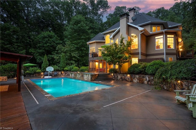 pool at dusk featuring a patio