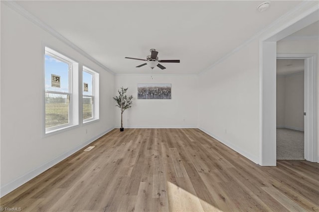 spare room featuring crown molding, light wood-style flooring, and baseboards