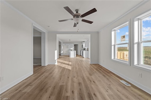 unfurnished living room featuring visible vents, a healthy amount of sunlight, and ornamental molding