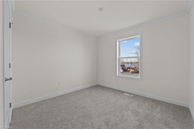 carpeted spare room with visible vents, baseboards, and ornamental molding