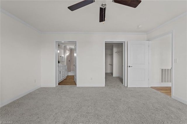 unfurnished bedroom with visible vents, carpet flooring, crown molding, and a walk in closet