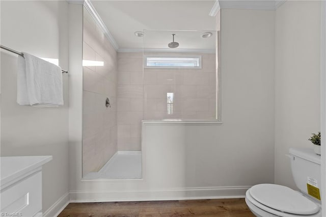 full bathroom with baseboards, tiled shower, toilet, and wood finished floors