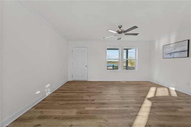 empty room featuring baseboards, crown molding, a ceiling fan, and wood finished floors