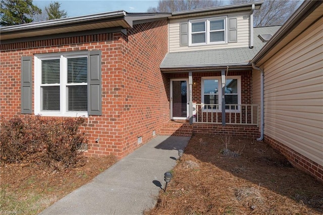 property entrance featuring crawl space, a porch, and brick siding