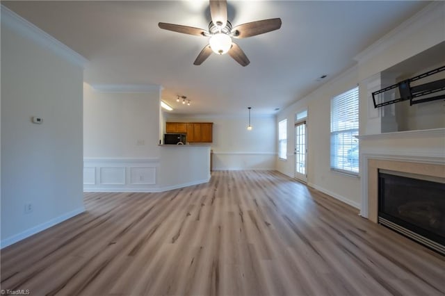 6015 Accord Ct, Pfafftown, NC 27040 - unfurnished living room featuring crown molding, a glass covered fireplace, ceiling fan, light wood finished floors, and wainscoting