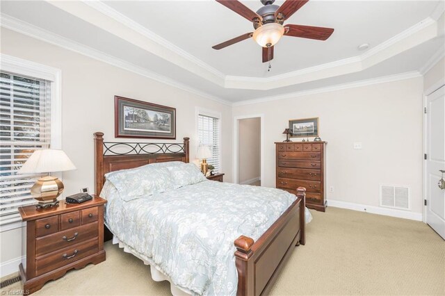 carpeted bedroom with ceiling fan, crown molding, and a tray ceiling