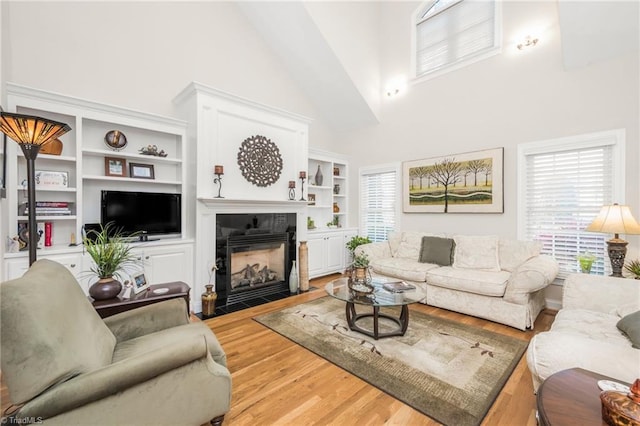 living room featuring hardwood / wood-style floors, high vaulted ceiling, a healthy amount of sunlight, and a tile fireplace