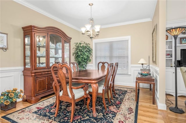 dining area with light hardwood / wood-style floors, crown molding, and an inviting chandelier