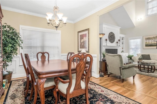 dining area with hardwood / wood-style flooring, a healthy amount of sunlight, ornamental molding, and a chandelier