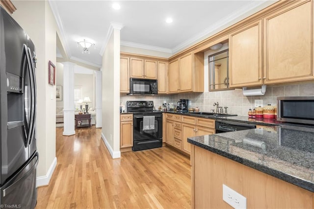 kitchen featuring dark stone counters, black appliances, light wood-type flooring, ornamental molding, and decorative columns