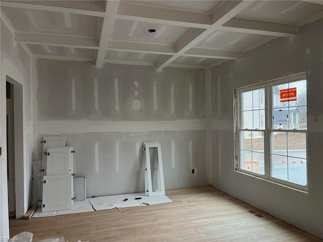 spare room featuring beamed ceiling, plenty of natural light, coffered ceiling, and light hardwood / wood-style floors