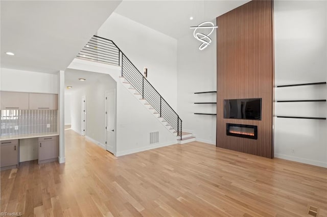 unfurnished living room with a large fireplace, built in desk, and light wood-type flooring