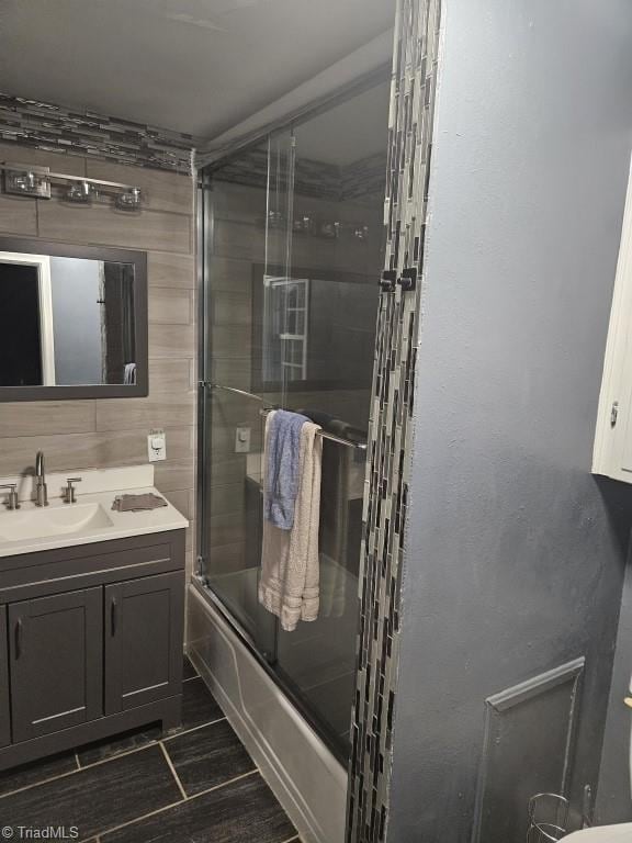 bathroom featuring combined bath / shower with glass door and vanity